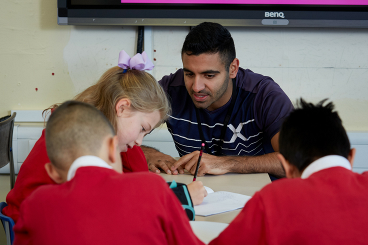 A teacher helping a school child with her Maths work